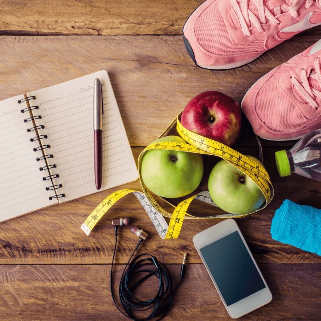 Notebook, apples and tape measure for planning fitness goals