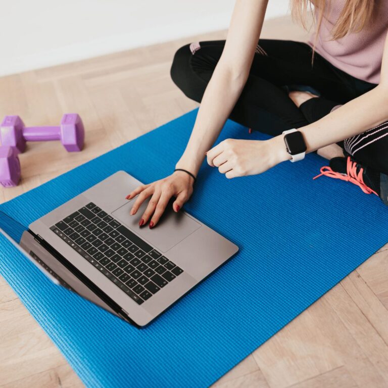 Online personal training on a laptop from a yoga mat